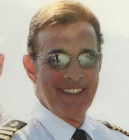 A man in uniform with glasses and smiling.